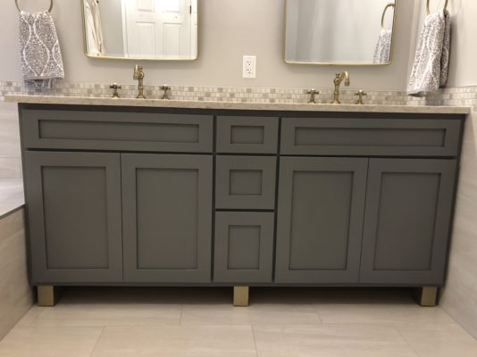 Custom maple bathroom vanity for a customer in Emerson finished in "Metro Grey" with metallic gold feet.